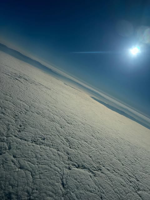 Sunrise above a solid cloud deck over the SoCal basin, sun flaring in a deep blue sky