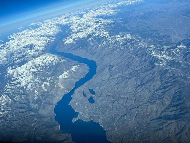 Lake Chelan winding between snow-dusted North Cascades ridges seen from high altitude